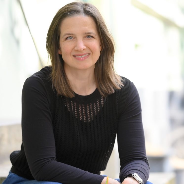 Julia Sittmann lächelt in die Kamera. Der Hintergrund ist hell und verschwommen.