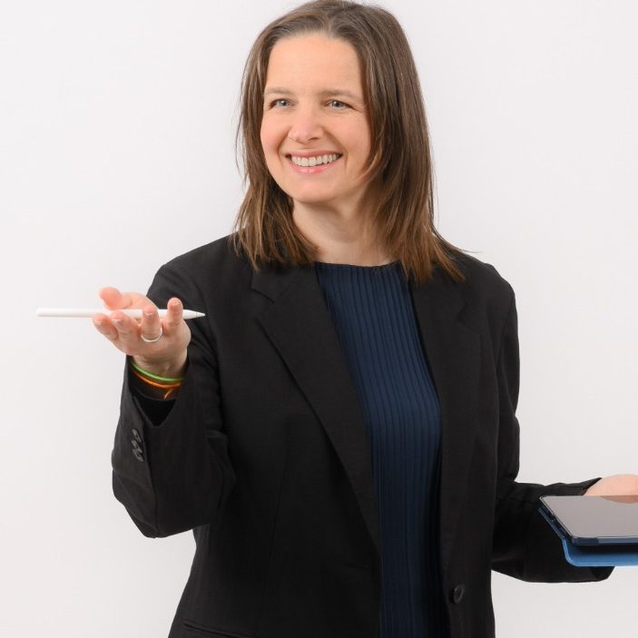 Julia Sittmann, Beraterin und Coach, fordert lächelnd eine Person außerhalb des Bildes auf, etwas zu sagen.